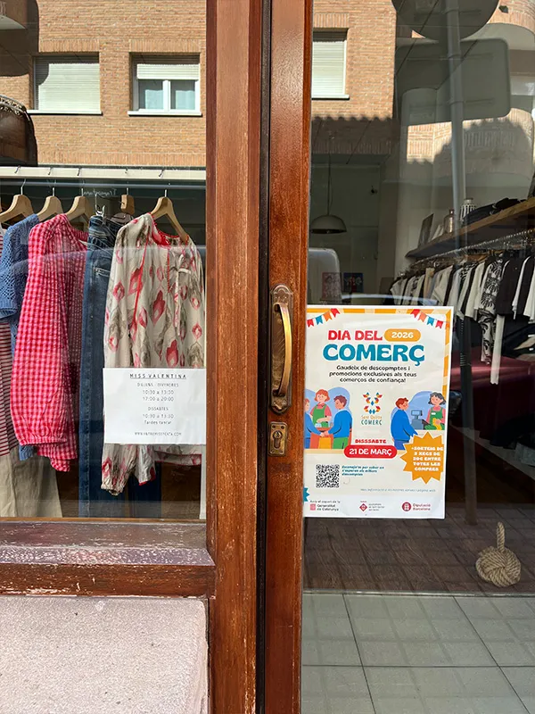 Aparador d’una botiga de roba amb el cartell del Dia del Comerç a Sant Quirze